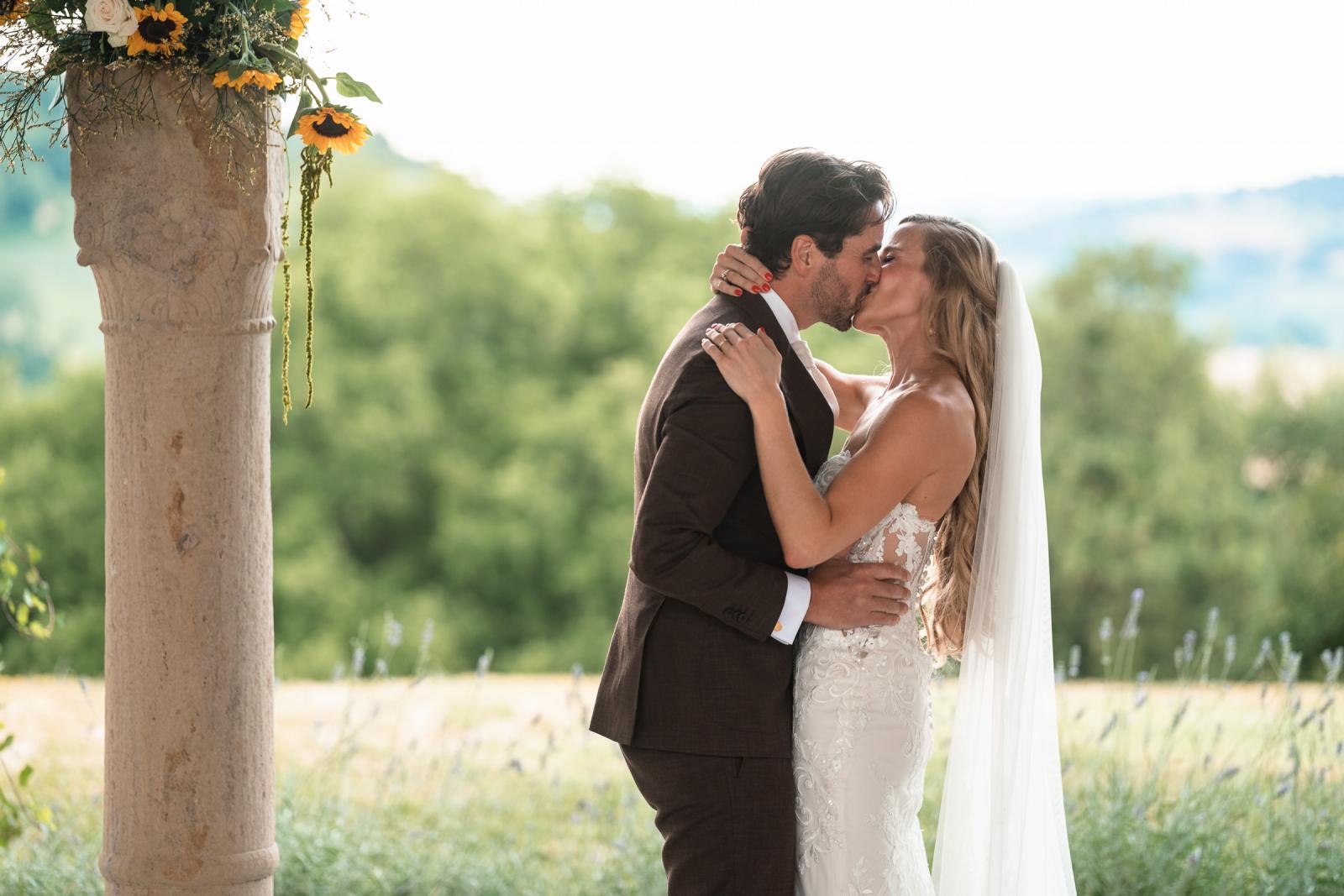Bride Gemmy and groom Niels first kiss next to sunflower arrangement during ceremony