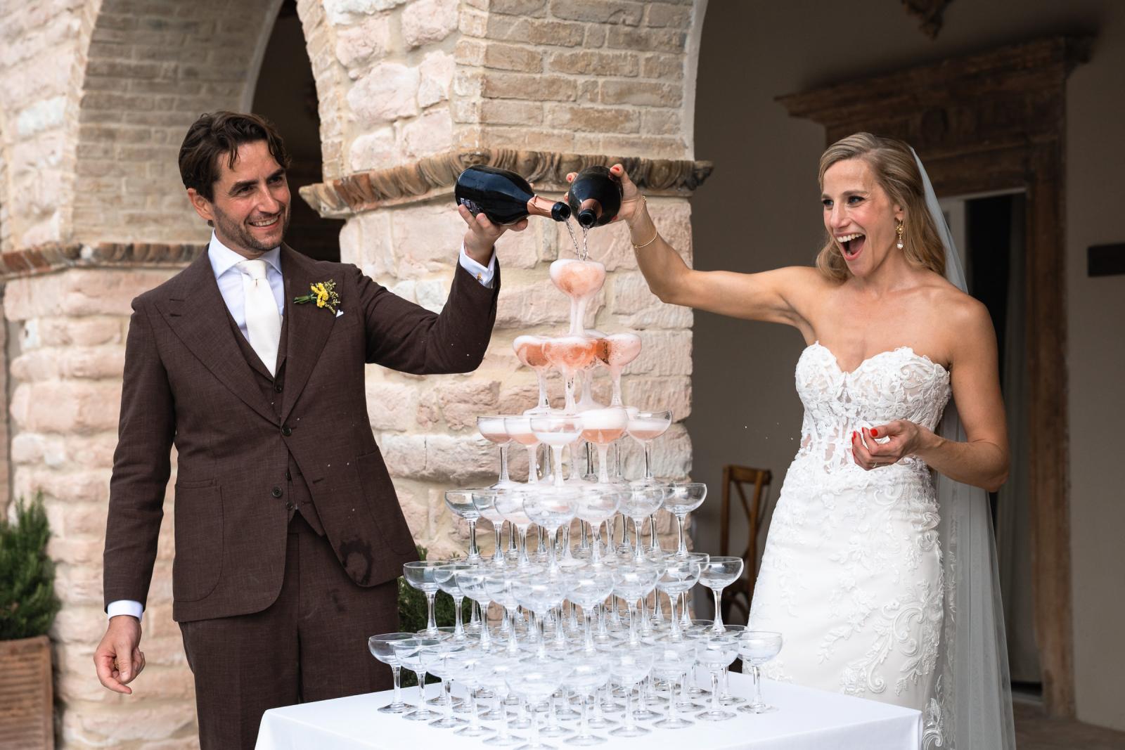 Bride Gemmy and groom Niels pouring champagne tower during outdoor wedding reception