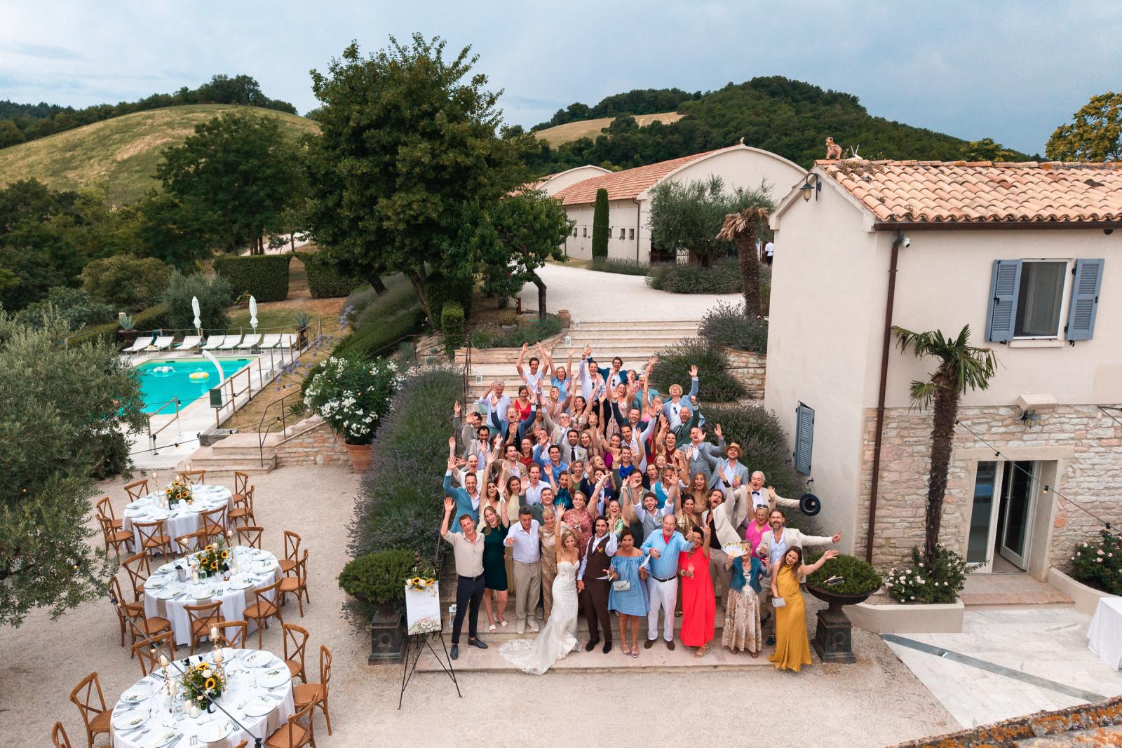 Aerial shot of full wedding group photo on steps at Le Stonghe venue