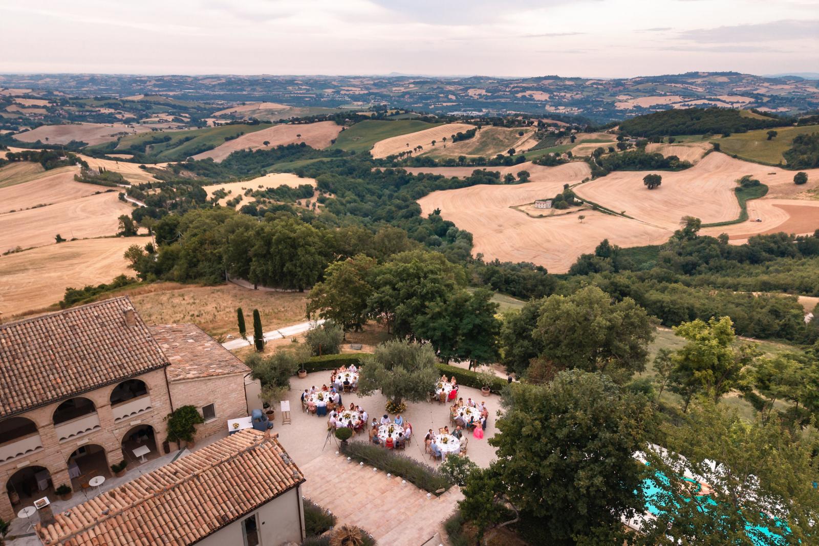 High angle drone shot of outdoor wedding reception area and surrounding Italian countryside