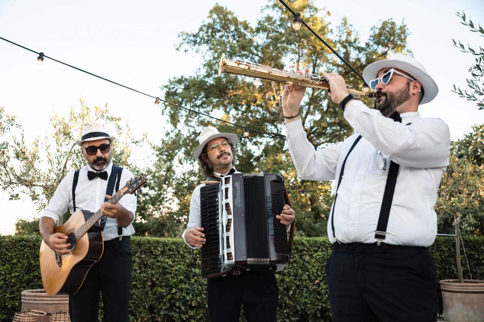 Live Italian trio with accordion, guitar, and soprano saxophone performing at a wedding party