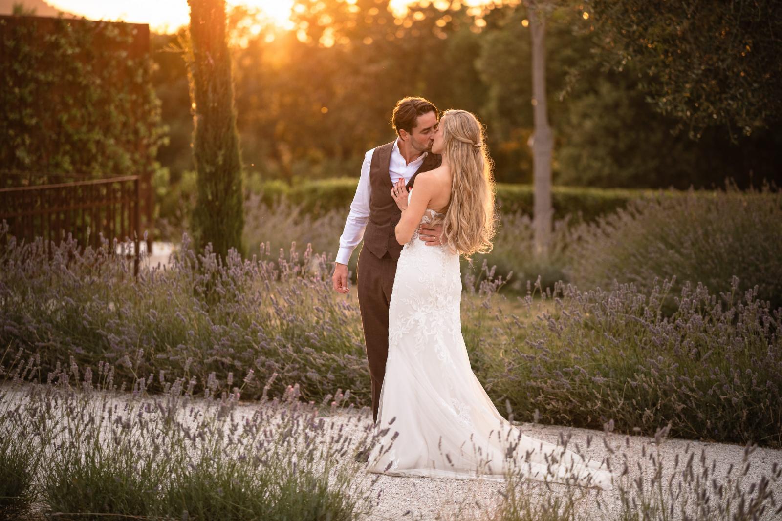 Groom Niels kissing bride Gemmy surrounded by lavender bushes during golden hour portrait session
