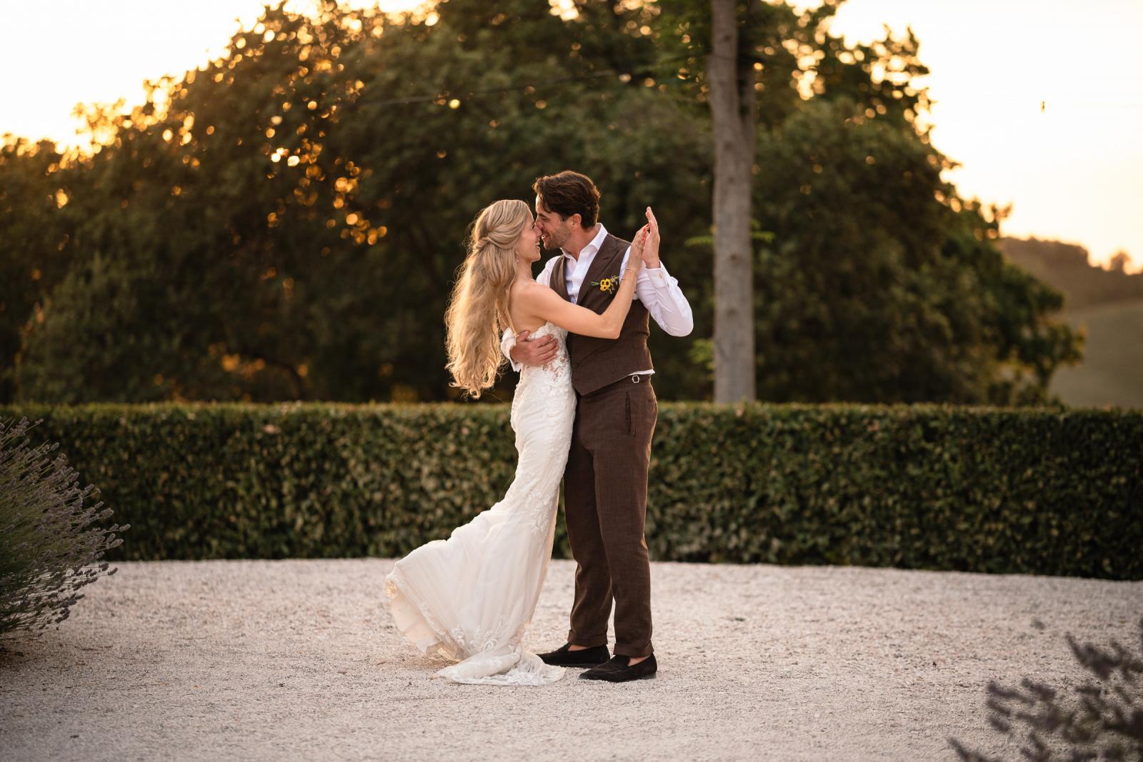 Bride Gemmy and groom Niels dancing together outdoors on gravel ground at sunset