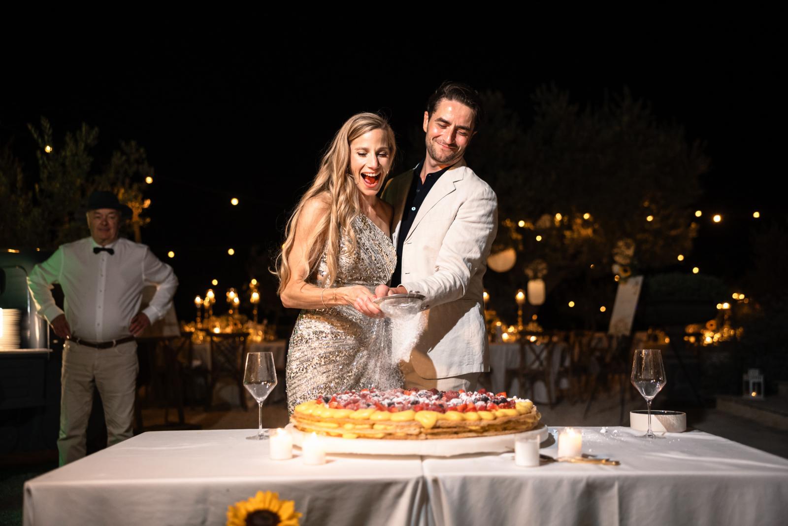 Bride Gemmy and groom Niels dusting powdered sugar over traditional Italian wedding cake