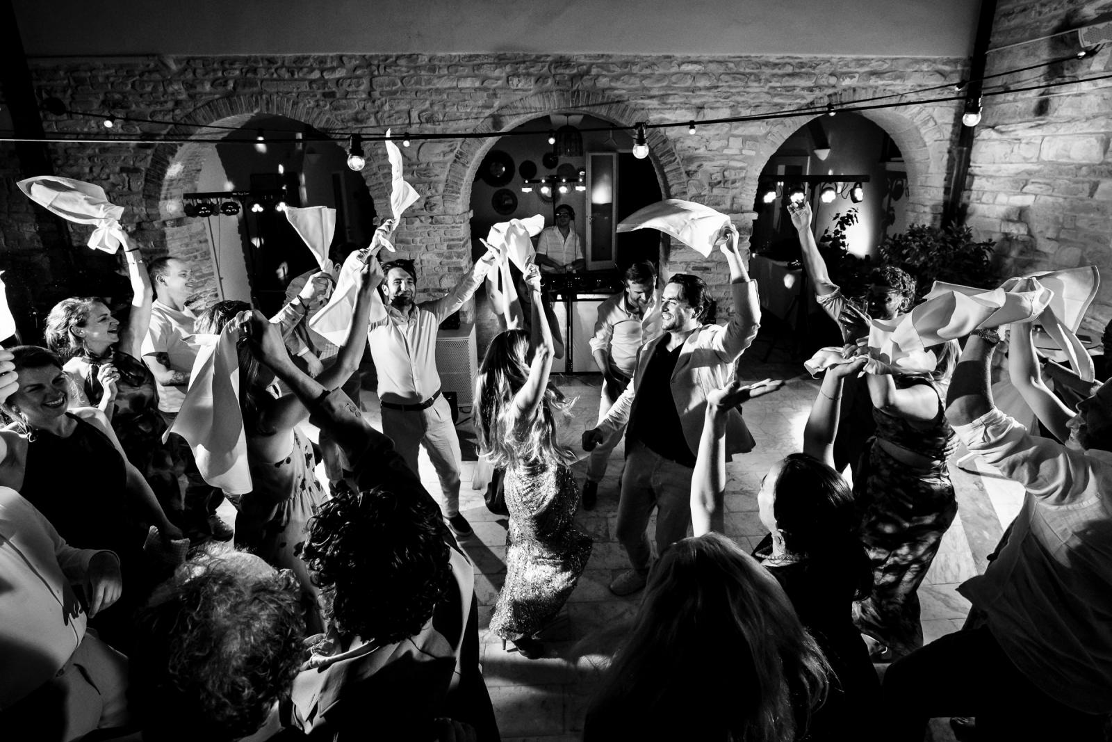 Black and white overhead view of bride Gemmy and groom Niels dancing surrounded by napkin-waving guests