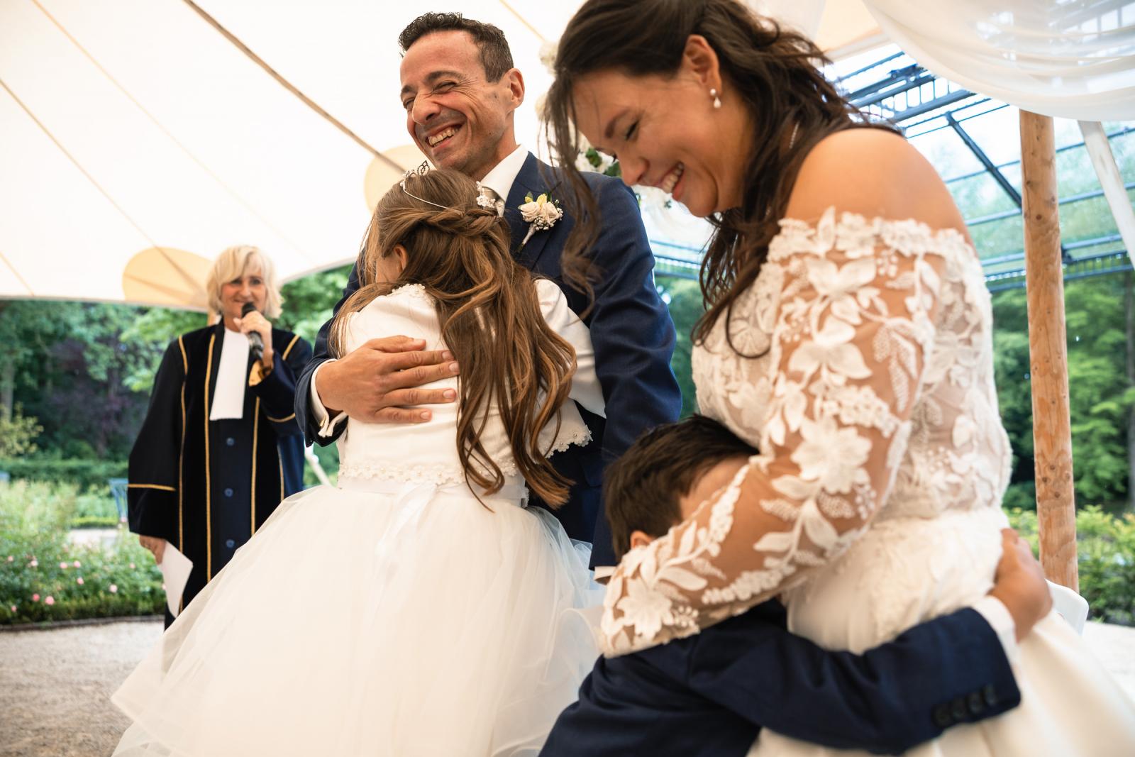 Liefdevolle knuffel tussen George, Iris en hun kinderen direct na de huwelijksvoltrekking tijdens de ceremonie.