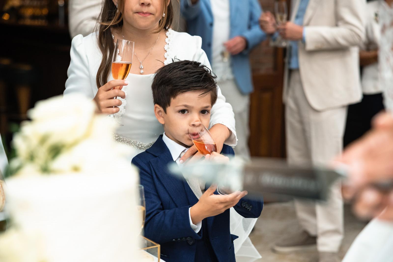 Dichtbij opname van het zoontje dat geniet van een glas kinderchampagne tijdens het proostmoment.