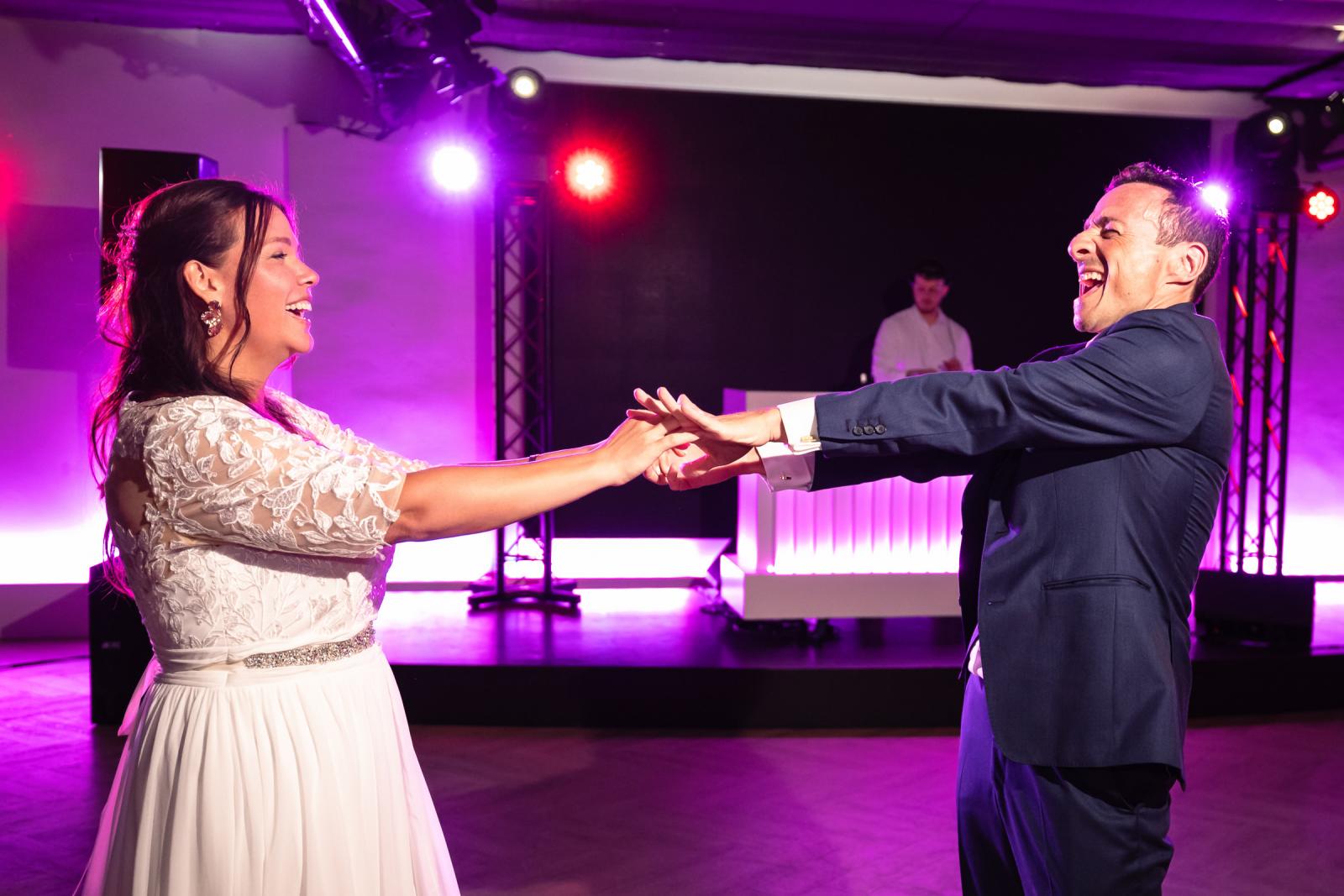 Stralend moment tijdens de openingsdans waar George en Iris elkaar lachend bij de handen vasthouden op de dansvloer.