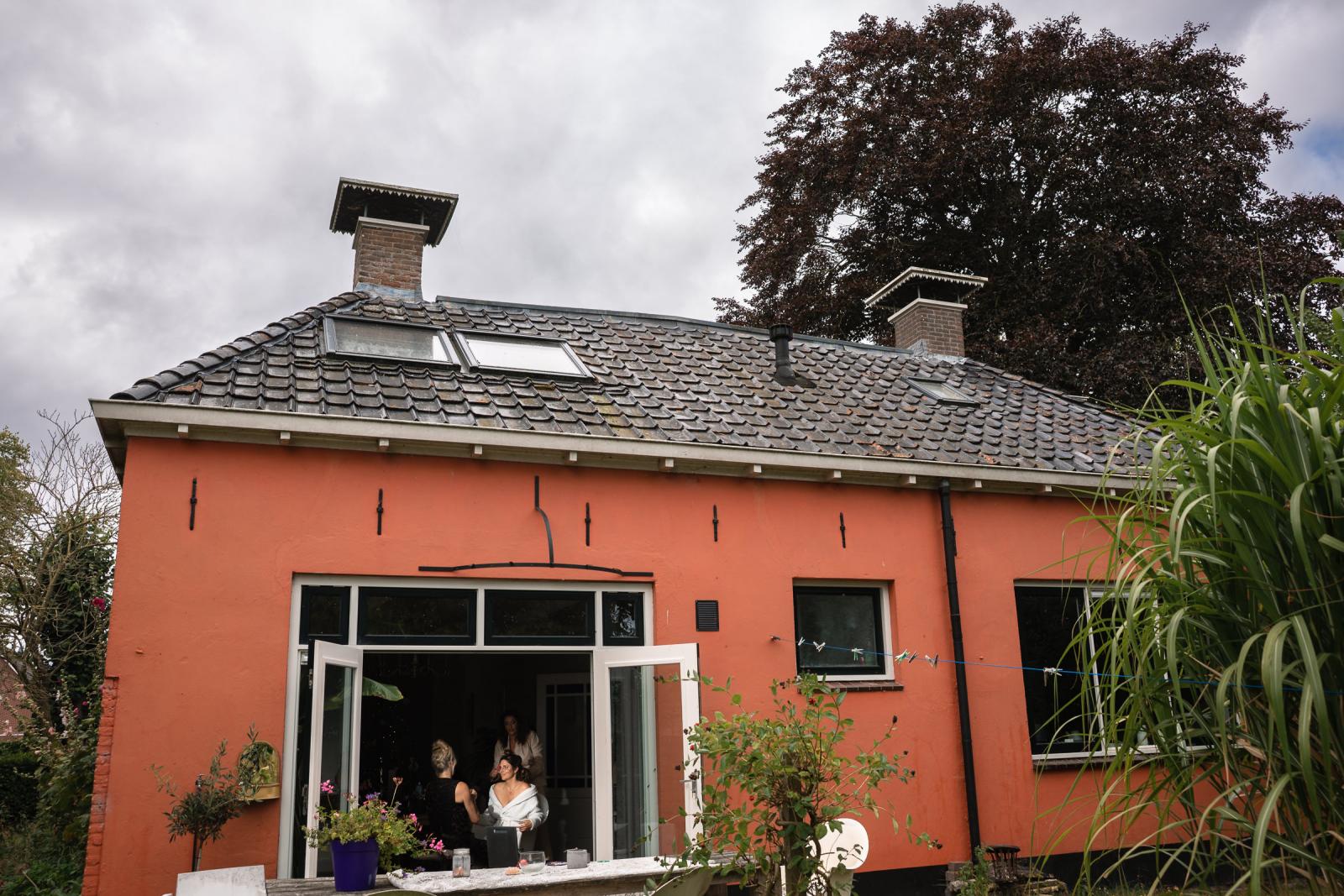 Voorbereidingen bruiloft in Friesland – Chantal maakt zich klaar bij de buren, gezien vanuit de tuin.