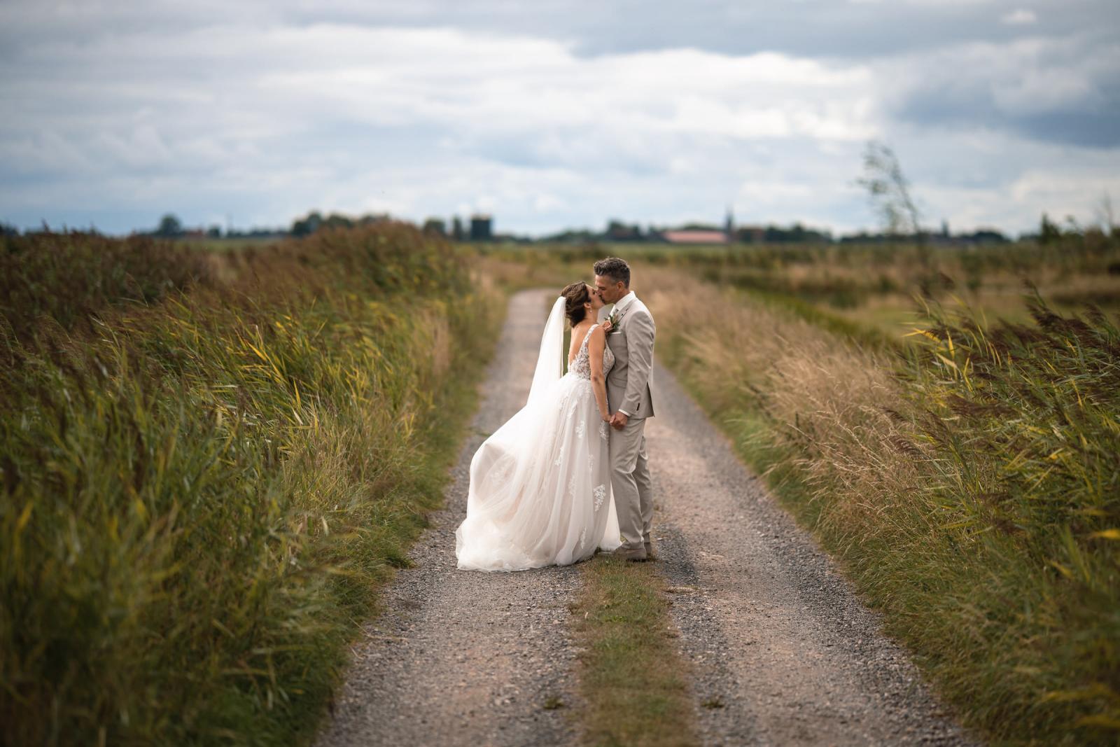 Romantische kus van Gerrit en Chantal op een landelijke weg tussen het hoge gras.
