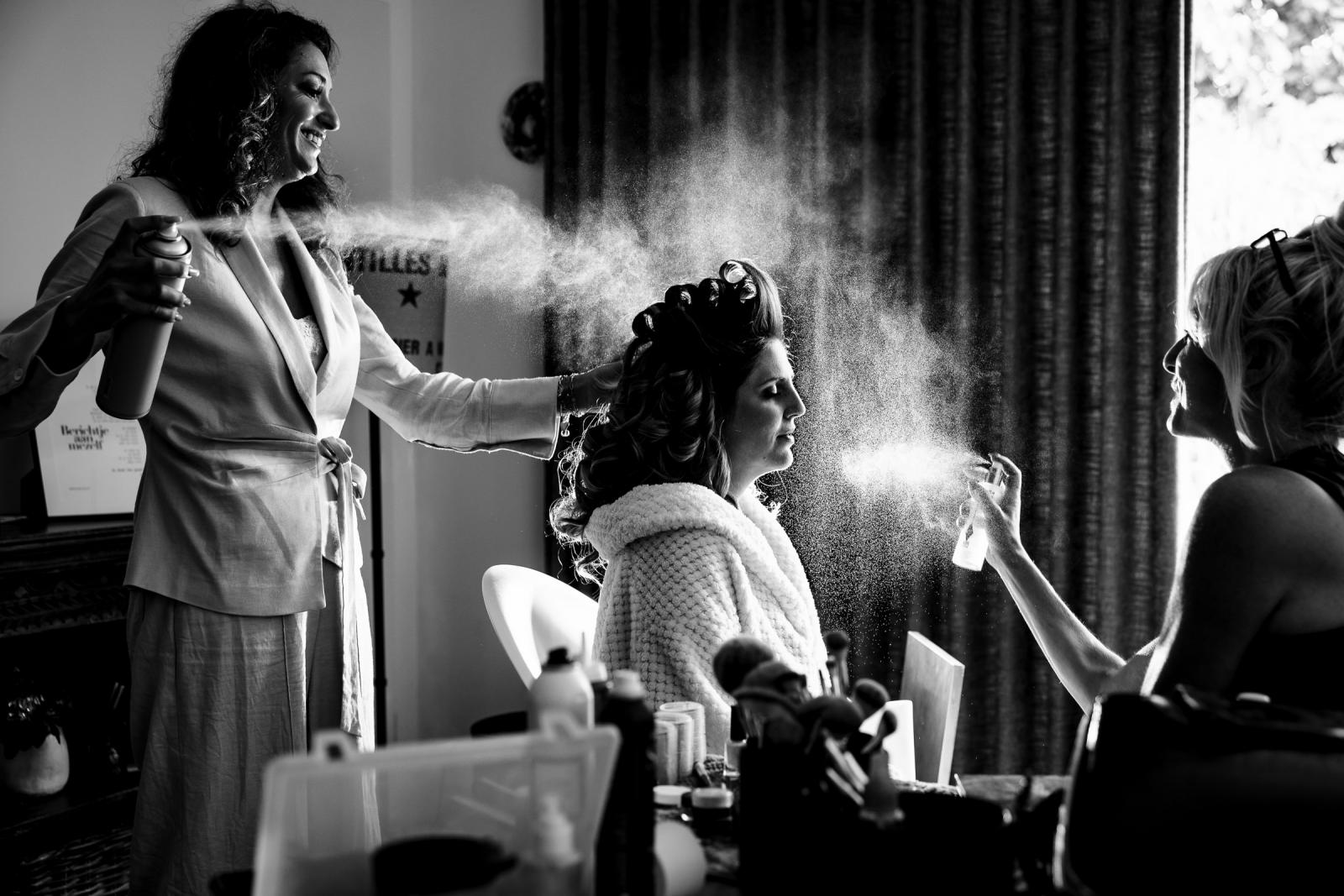 Vriendinnen en visagist verzorgen het haar van bruid Chantal tijdens de ochtend voorbereidingen.