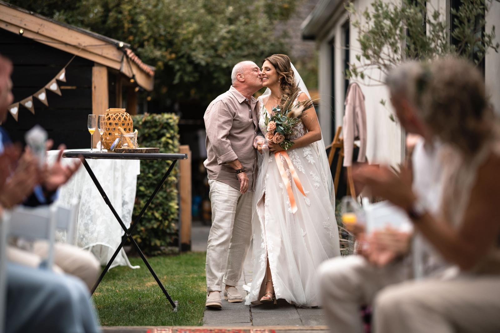 Vader kust de bruid op haar wang terwijl hij haar wegbrengt naar de ceremonie.