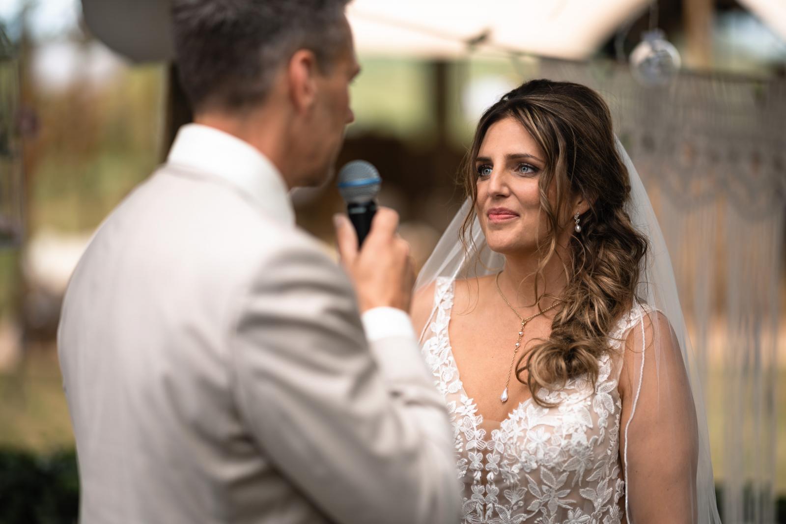 Bruid en bruidegom kijken elkaar liefdevol aan tijdens het uitspreken van hun geloften.