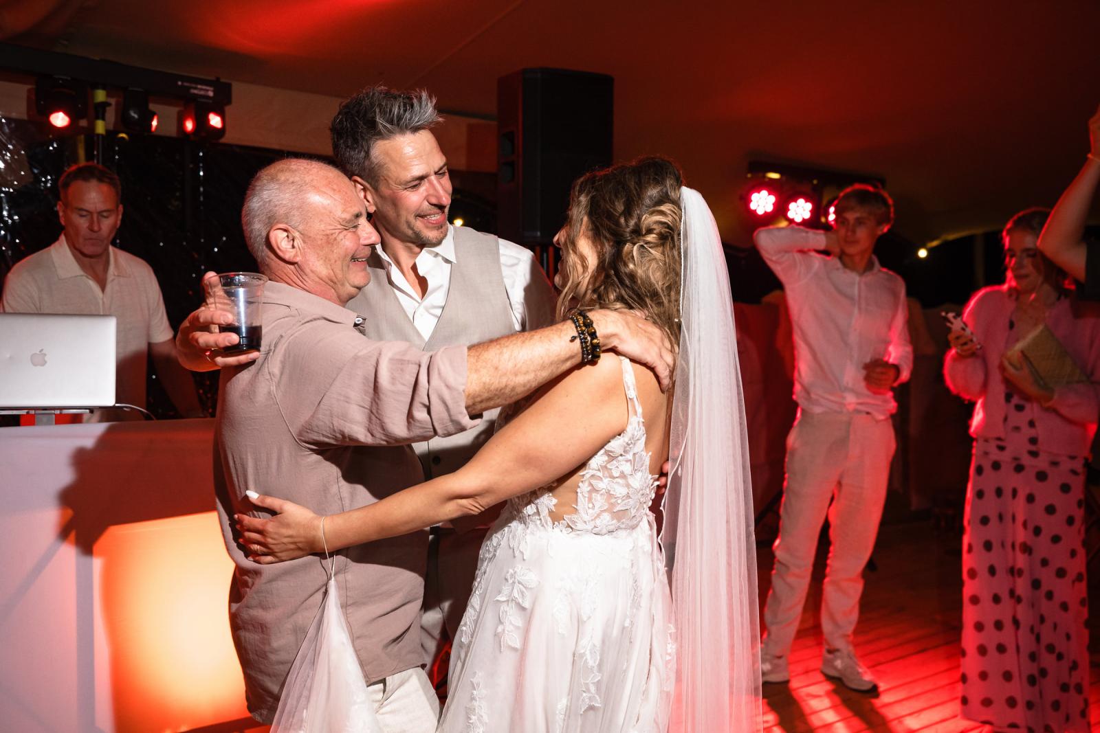 Close-up van van Gerrit en Chantal met haar vader, met kleurrijke feestverlichting.