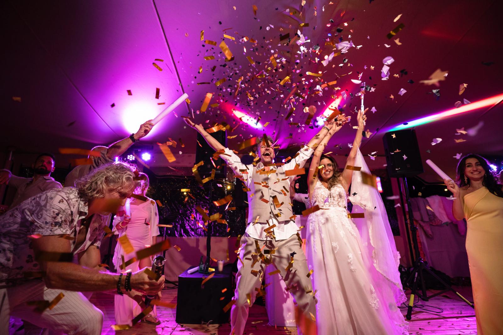 Bruidspaar onder confetti spray op de dansvloer van hun trouwfeest