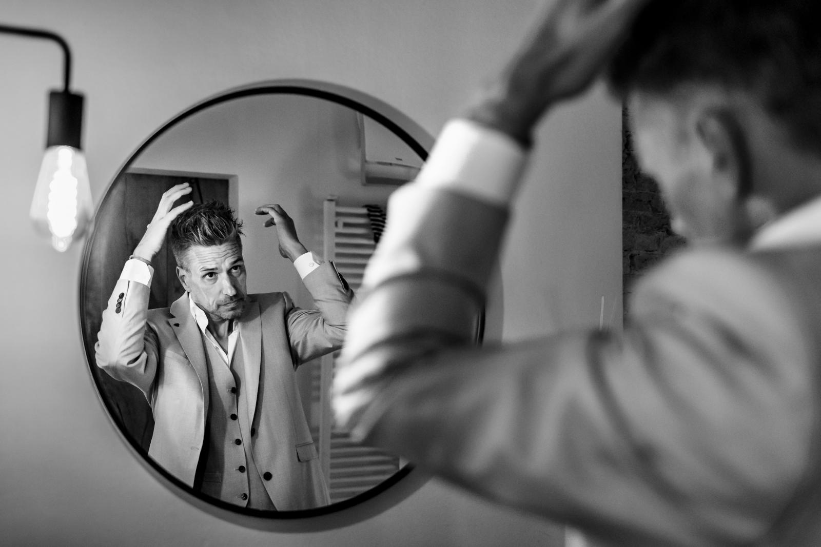 Bruidegom Gerrit kijkt in de spiegel en doet zijn haar goed voor de bruiloft.