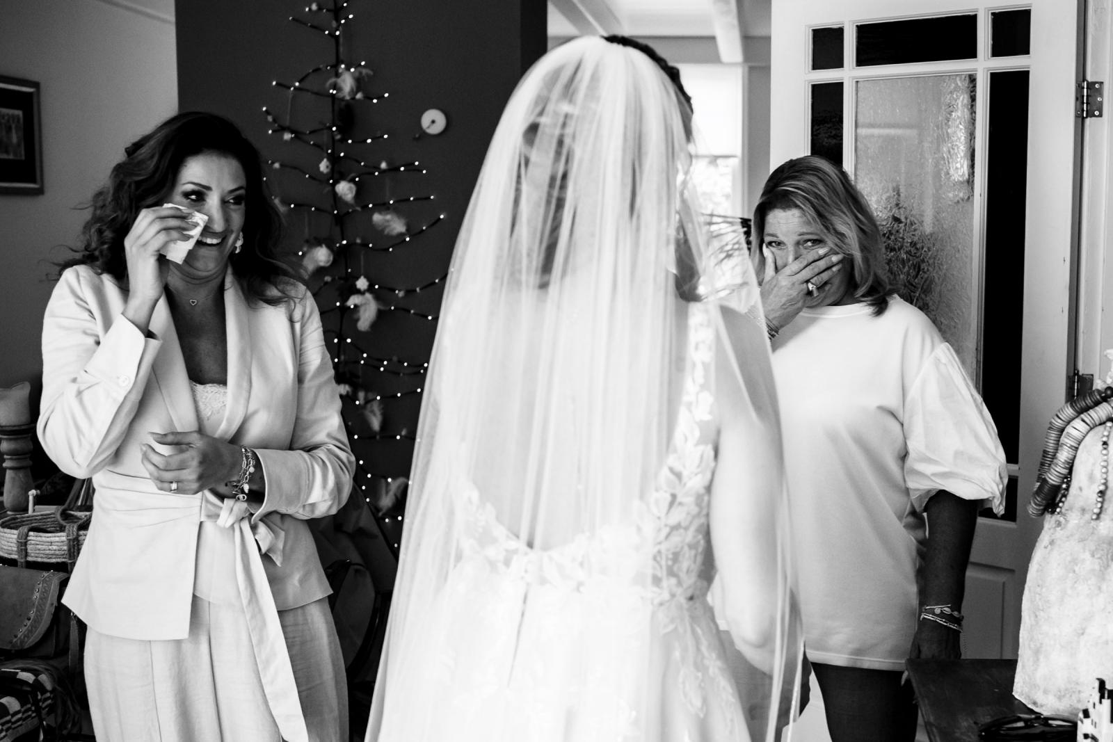 Emotioneel moment wanneer vriendinnen en moeder de bruid voor het eerst in trouwjurk zien.