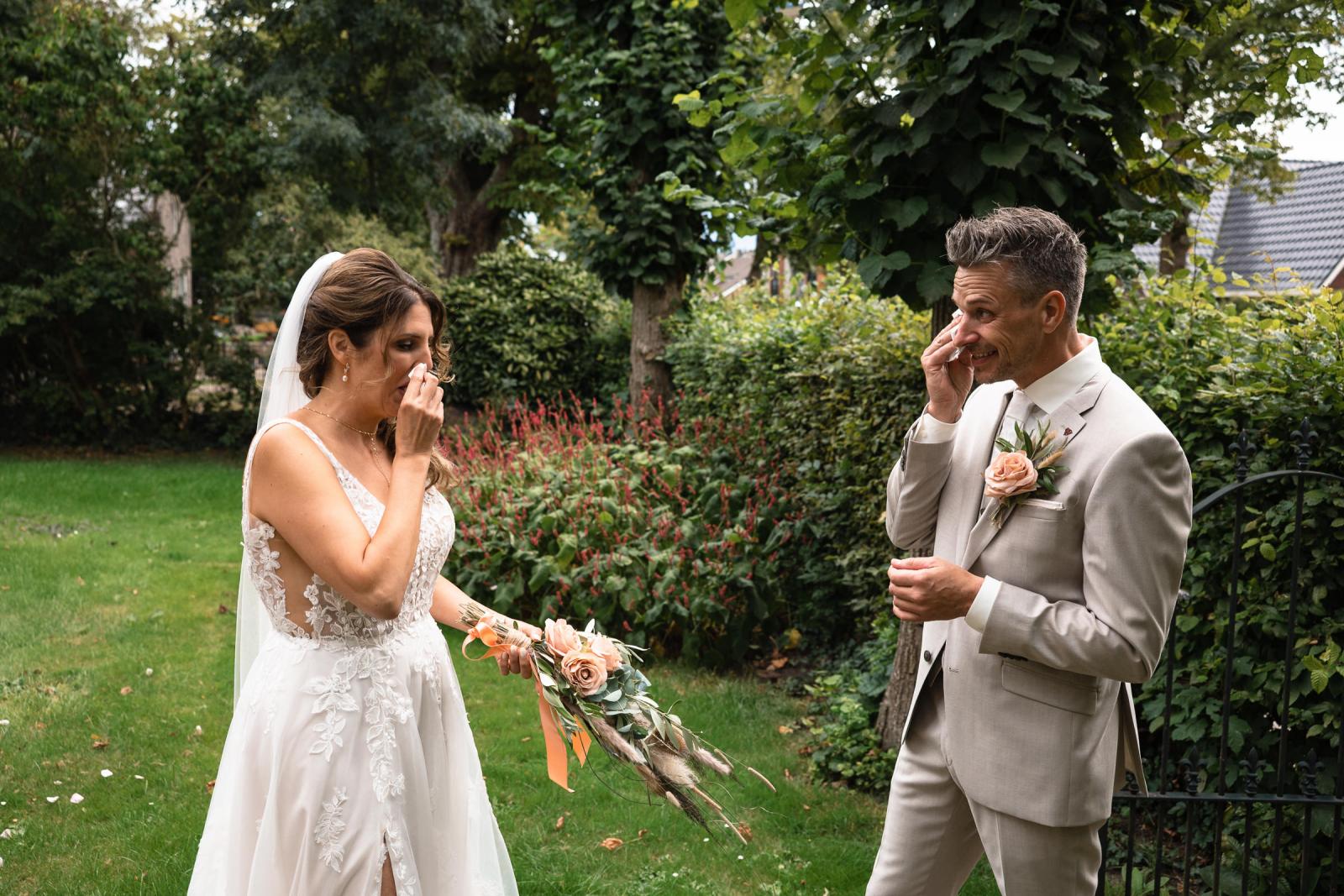 Emotionele first look in de tuin, zowel bruid als bruidegom vegen tranen van geluk weg.