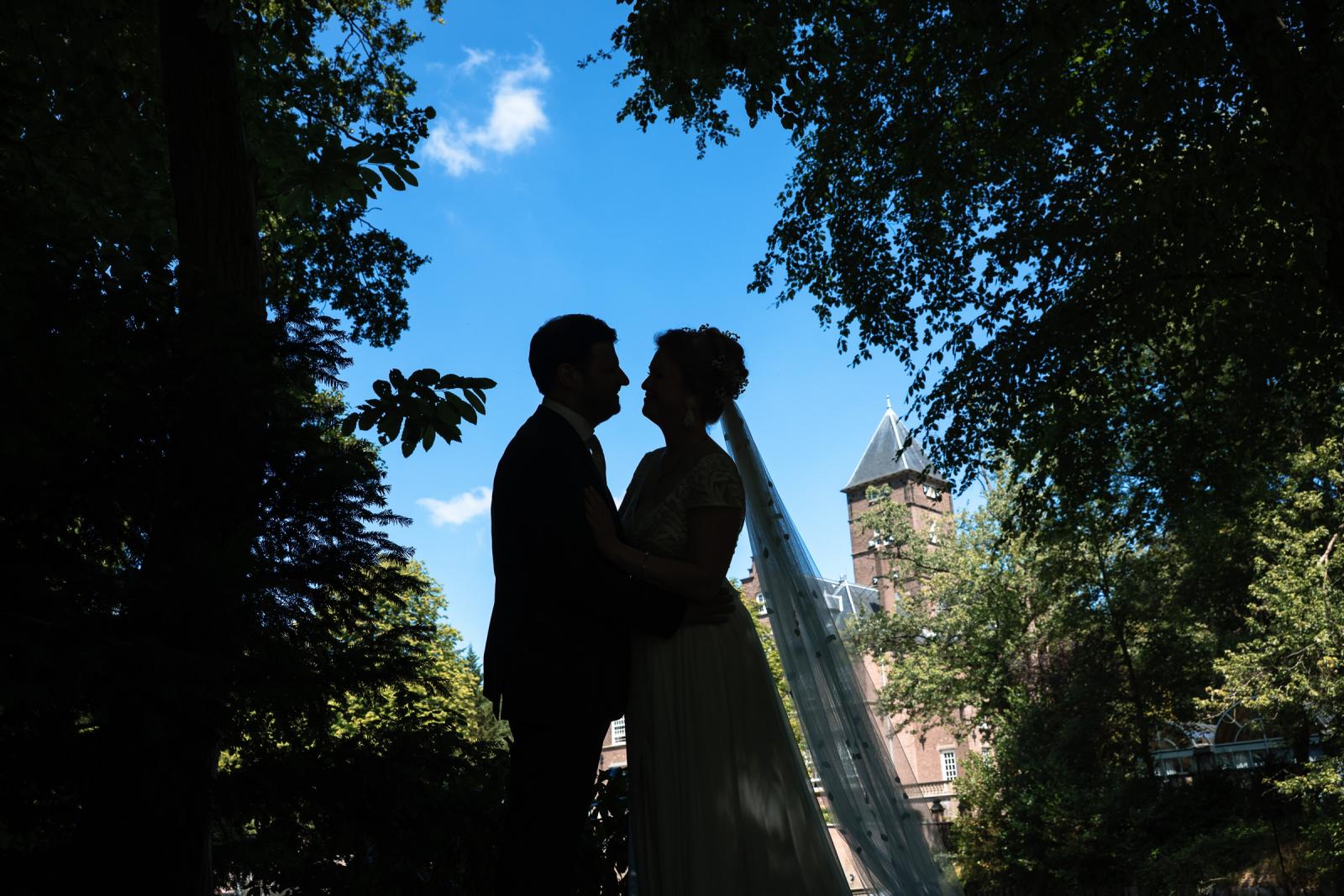 Silhouette foto van het bruidspaar met een historisch kasteel op de achtergrond.