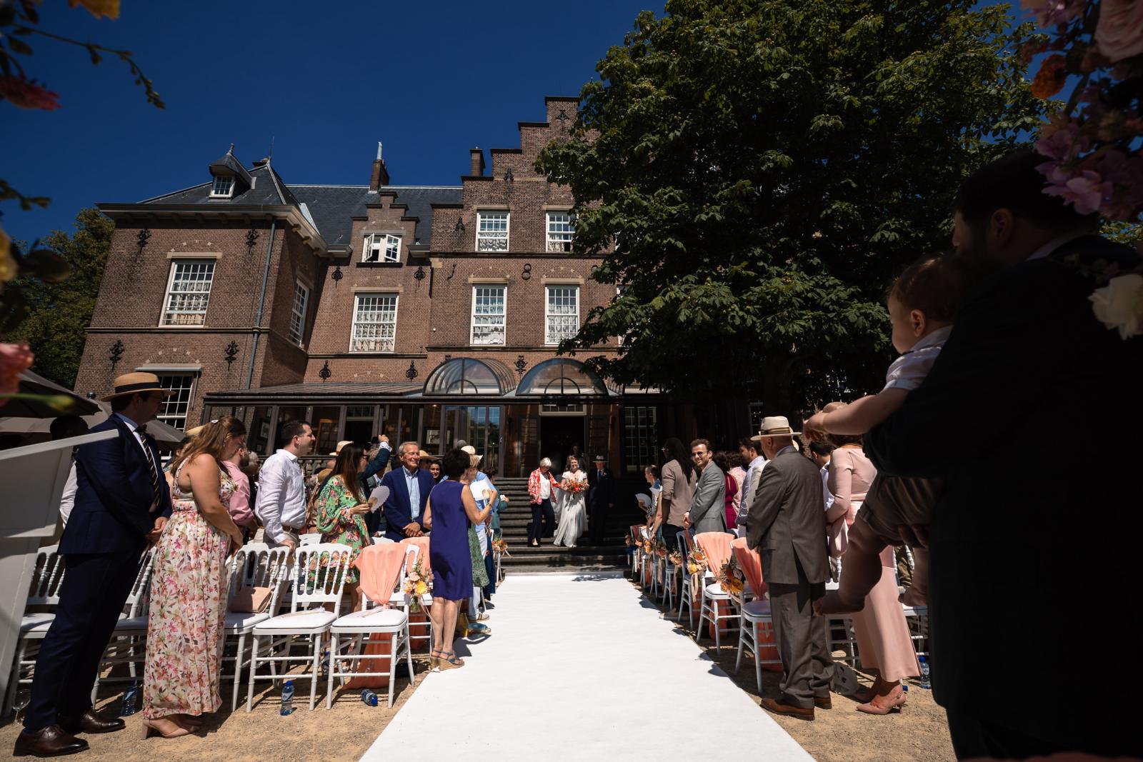 Bruid Hanneke komt aan op de witte loper bij de buitenceremonie voor het kasteel.