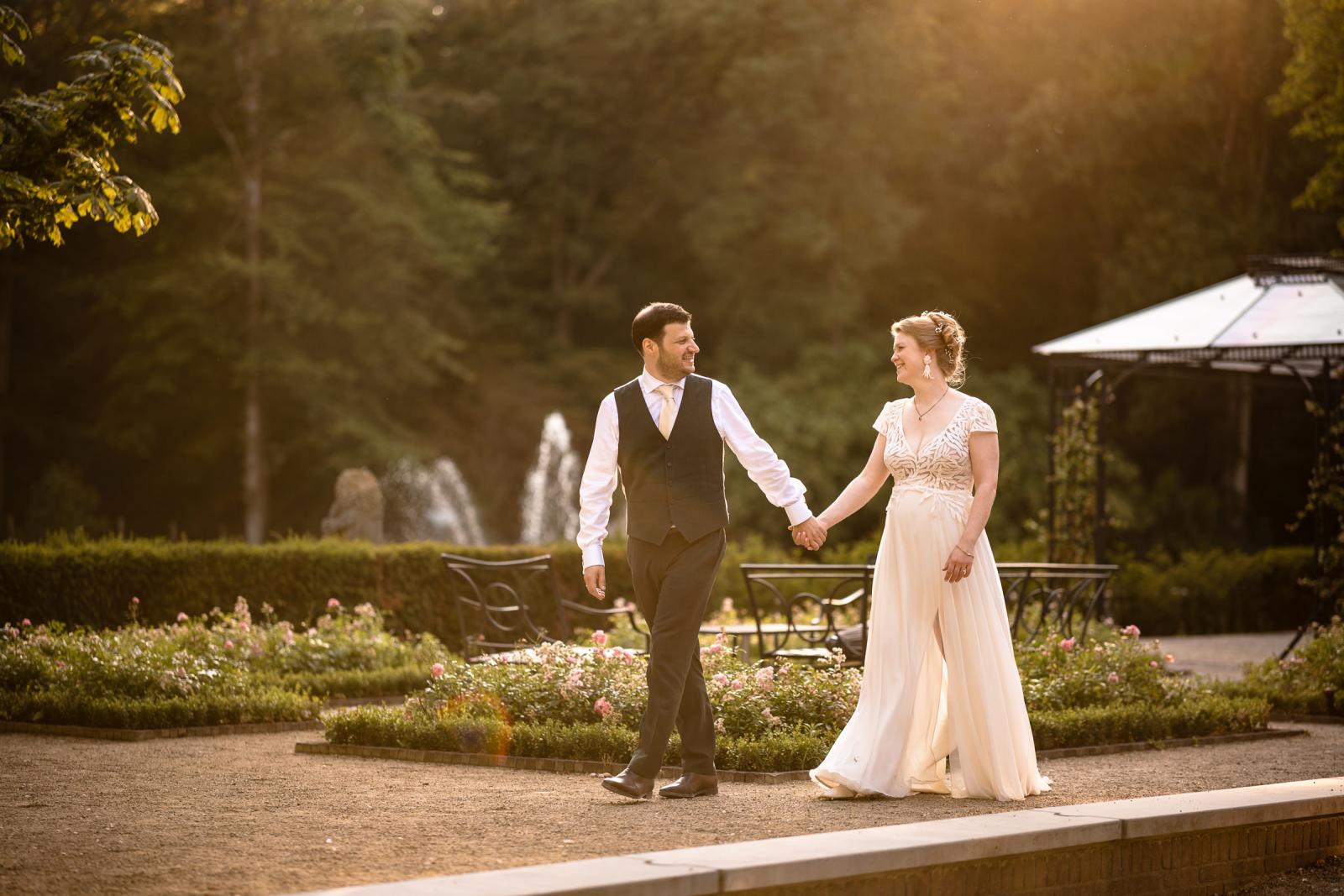 Romantische golden hour fotoshoot van bruid Hanneke en bruidegom Dennis wandelend door de kasteeltuin bij zonsondergang.