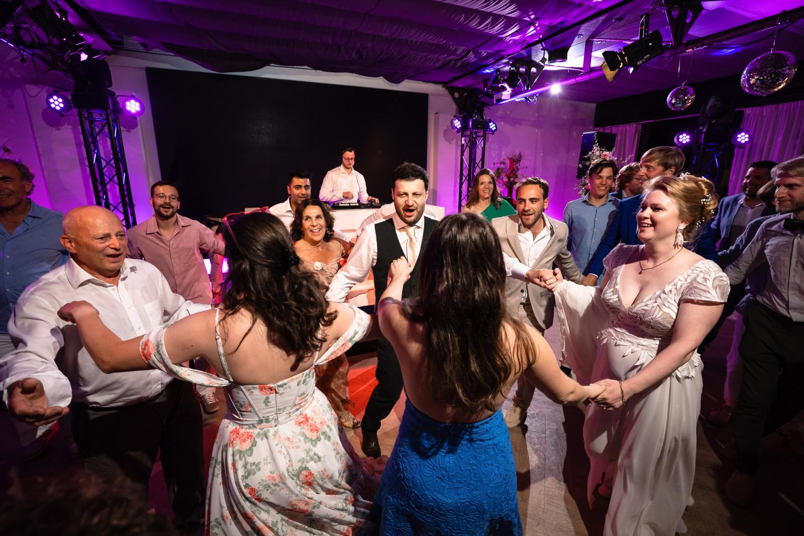 Bruidspaar en bruiloftsgasten dansen samen in een grote kring tijdens de traditionele Joodse Horadans.