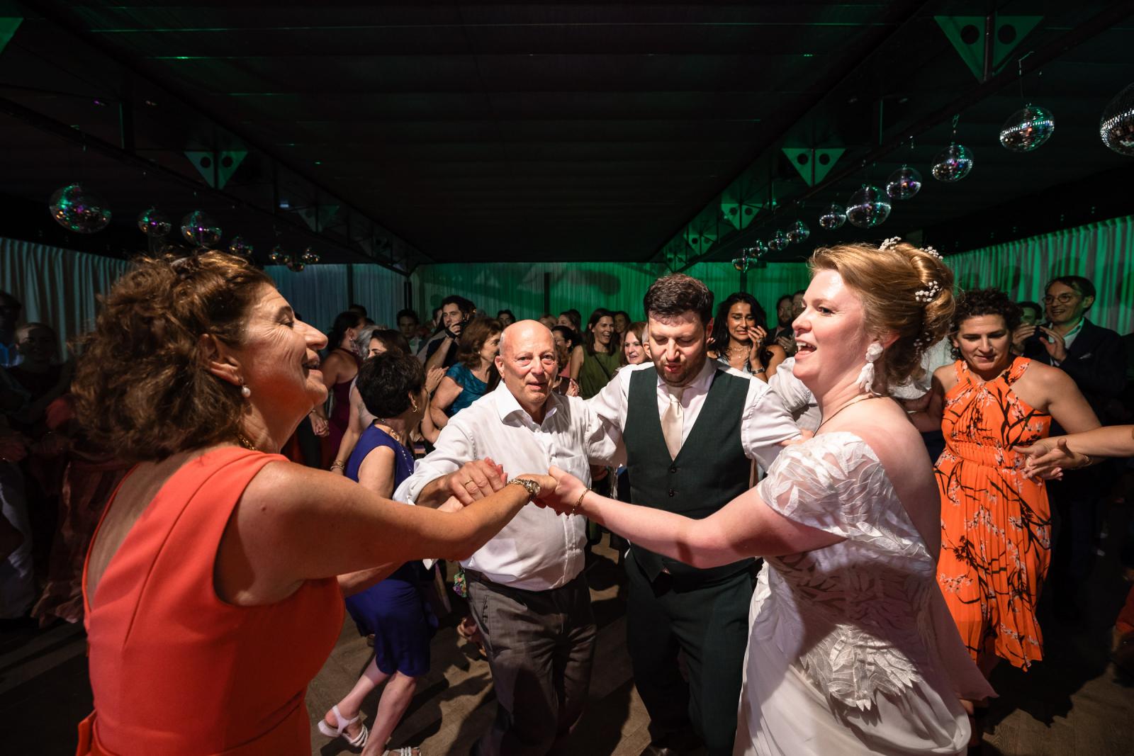 Bruid Hanneke en bruidegom Dennis dansen hand in hand in een vrolijke kring met hun familie en gasten.