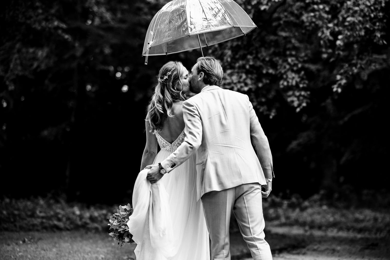 Fotoshoot bruidspaar kussend onder paraplu's bij Kasteel Oud Poelgeest 