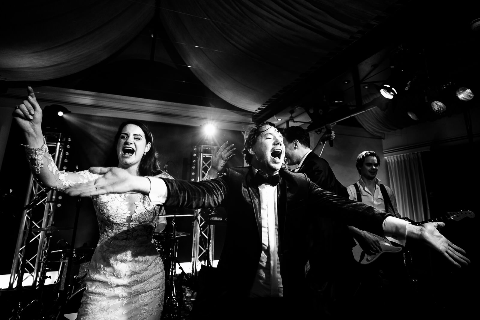 Bruidspaar samen zingend op podium tijdens hun huwelijks feest Trouwfotograaf Den Haag 