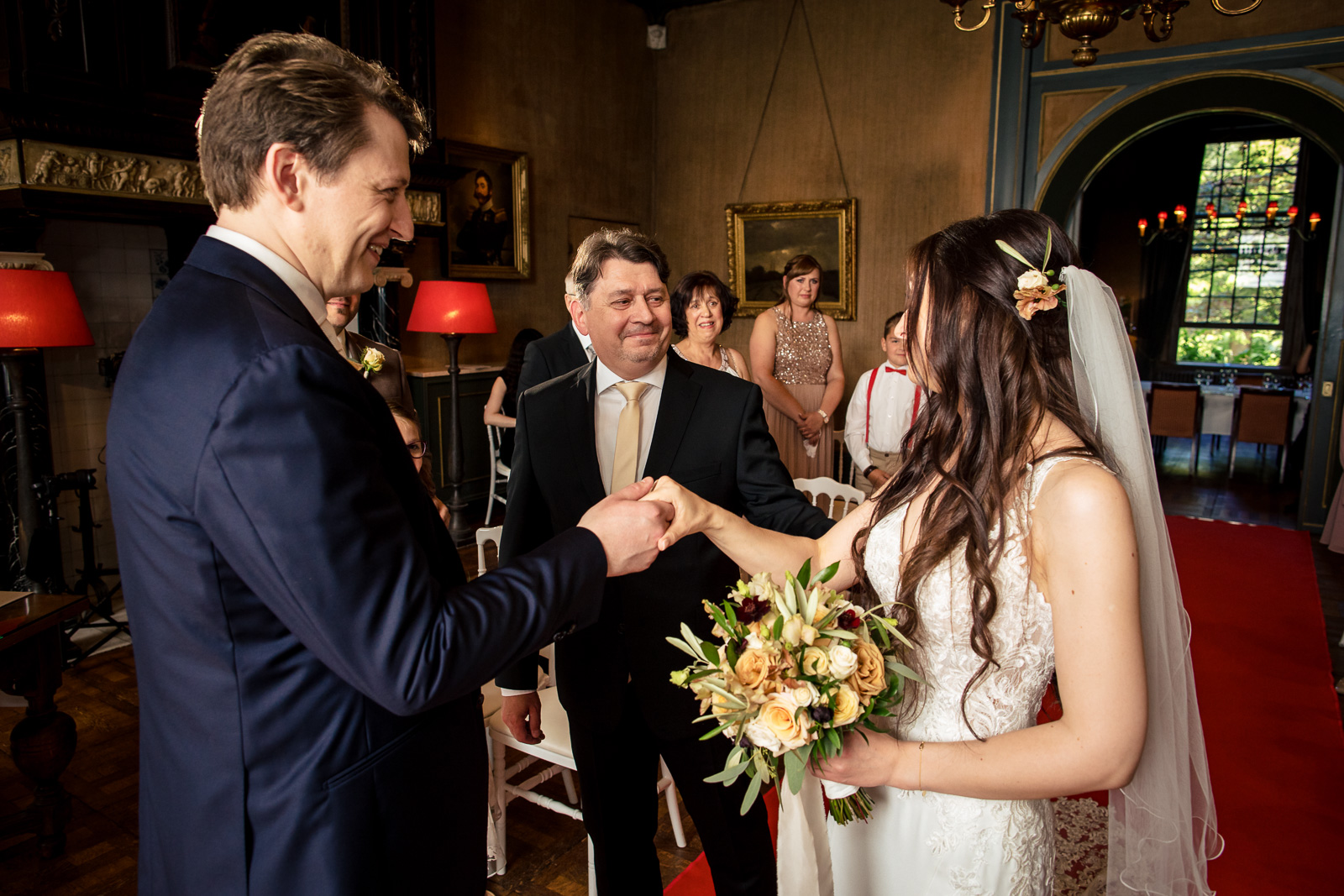 Vader van de bruid geeft z'n dochter over aan de bruidegom door kasteel trouwfotograaf