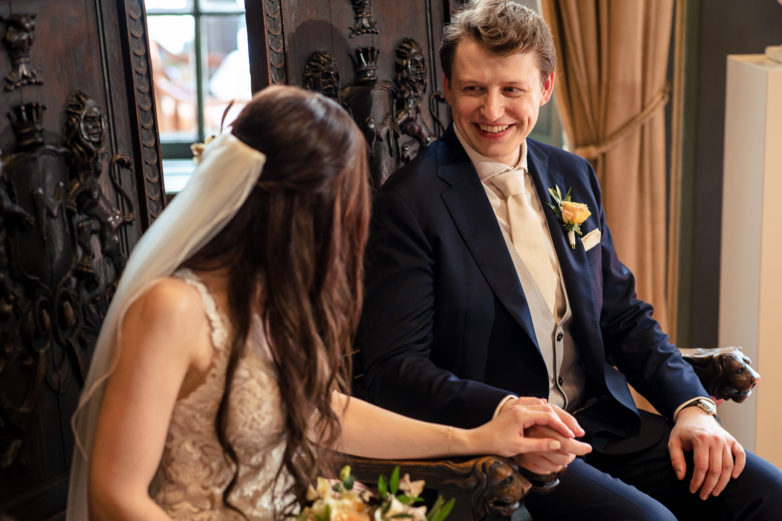 Liefdevolle blik van de bruidegom naar zijn bruid tijdens de kasteel trouwceremonie door kasteel trouwfotograaf