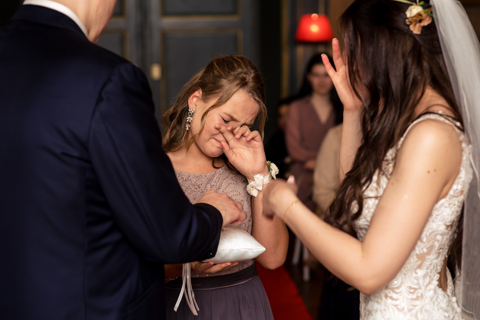 bruidsmeisje brengt met tranen in haar ogen de trouwringen door kasteel trouwfotograaf