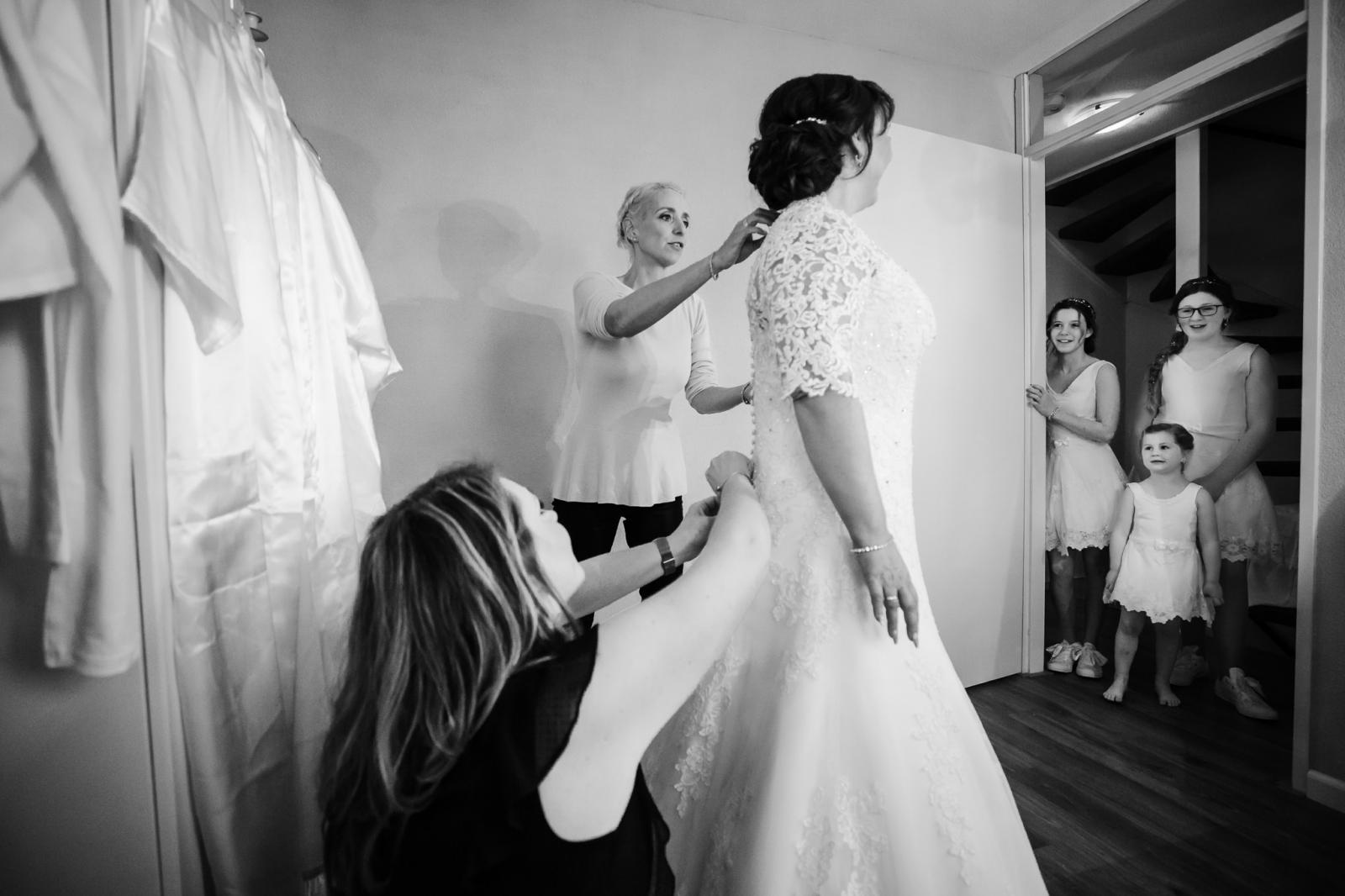 3 bruidsmeisjes kijken dromend over hun bruiloft naar hoe de bruid in haar trouwjurk gaat