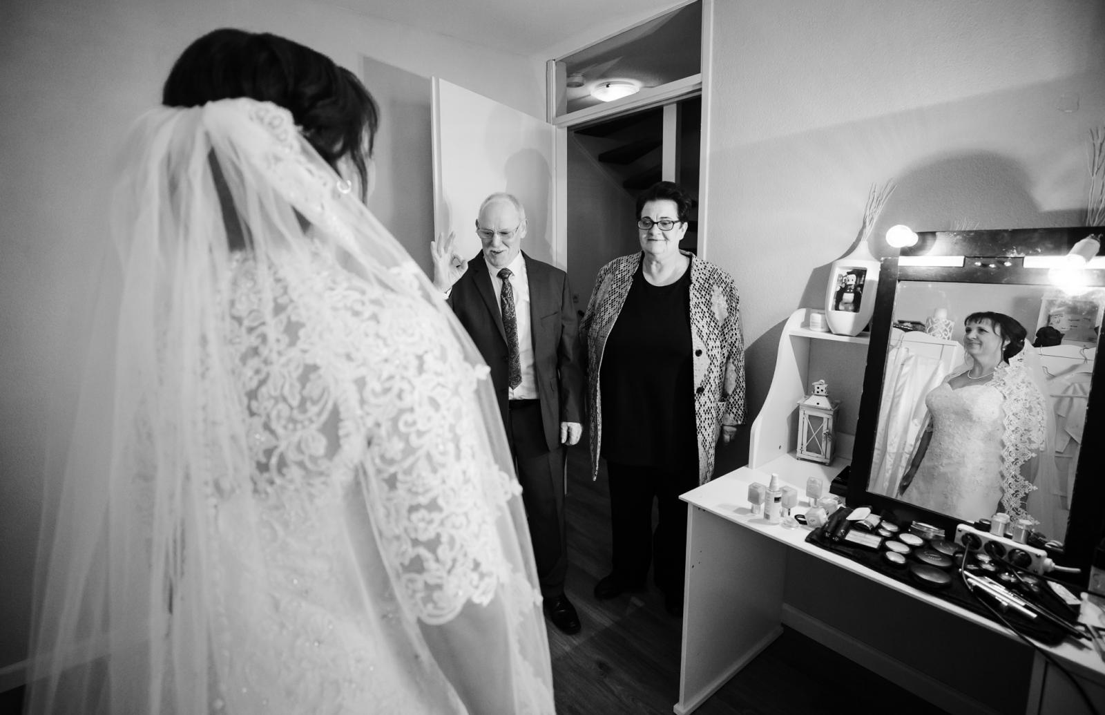 Vader en moeder van de bruid zien hun dochter voor het eerst in trouwjurk