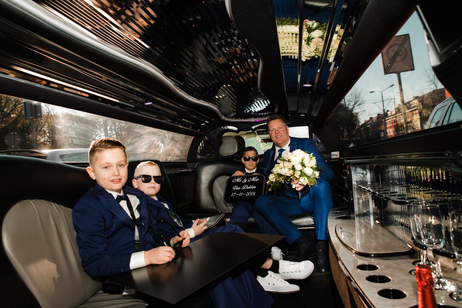 Bruidegom en bruidsjongens in de limousine om de bruid op te halen