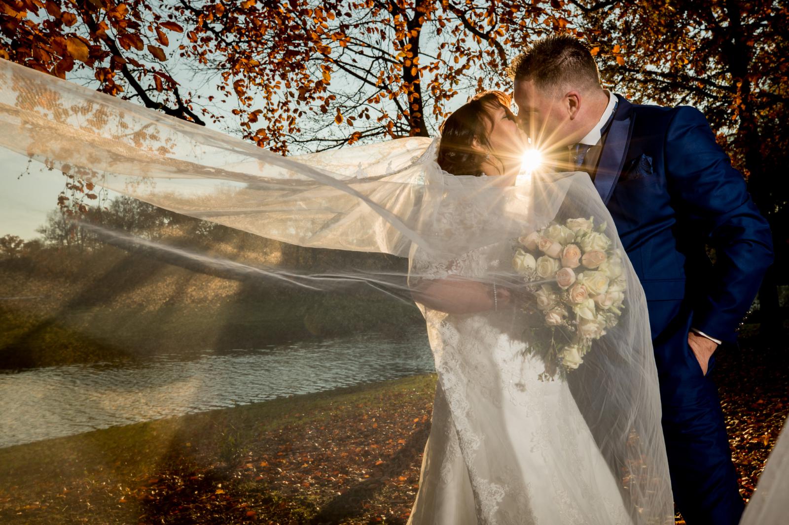 Bruidegom en bruid zoenen tijdens de herfst shoot kasteel oud wassenaar