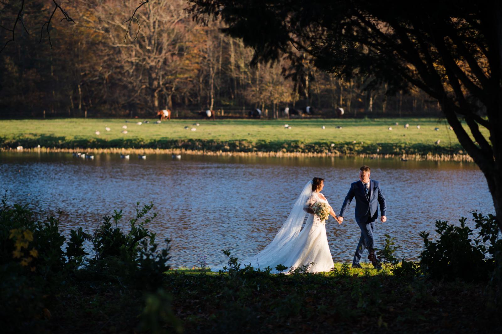 bruid en bruidegom wandelen richting zonsondergang tijdens de herfst shoot bij kasteel oud wassenaar