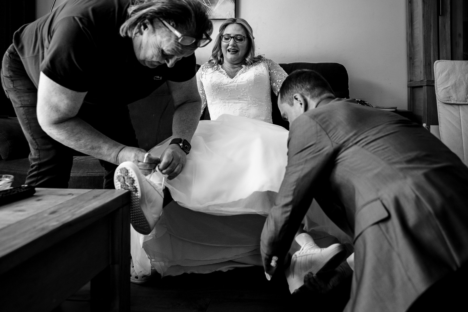 bruid krijgt hulp met schoenen aan doen Trouwfotograaf Spaansche Hof Den Haag