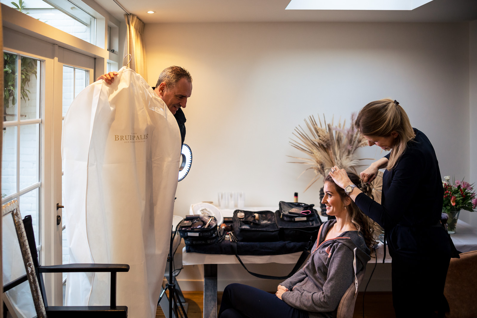 Vader komt binnen met de trouwjurk door Trouwfotograaf Den Haag Paco van Leeuwen