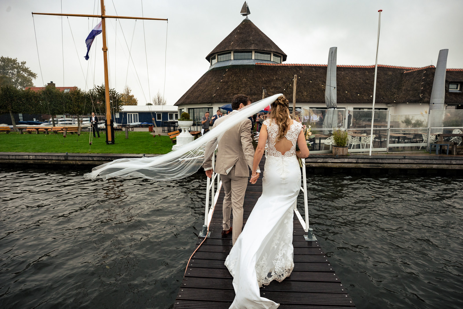 Herfstbruiloft bruidspaar komt aan bij trouwlocatie aan het water