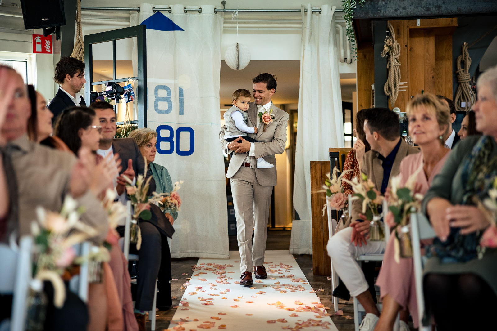 Herfstbruiloft bruiloft bruidegom komt met zoontje aanlopen voor de ceremonie Trouwfotograaf Den Haag Paco van Leeuwen