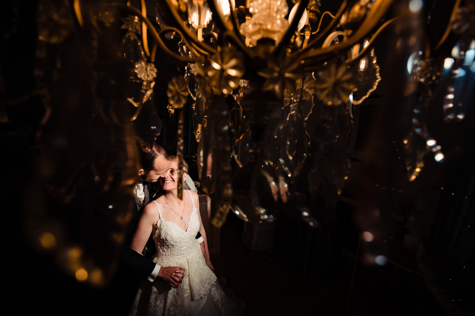 bruidspaar onder de kroonluchter gefotografeerd door Trouwfotograaf Wolvenbos