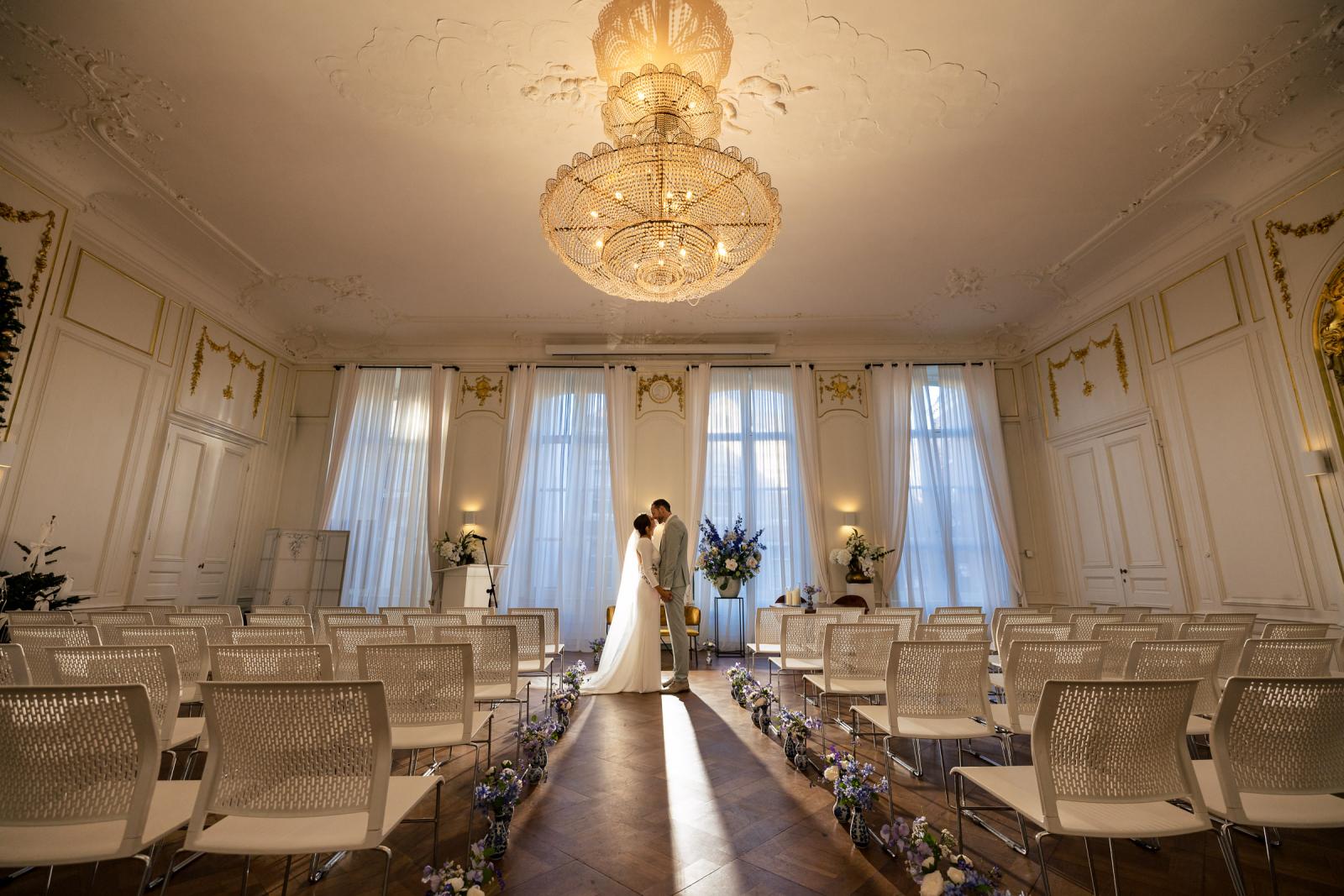 Bruid en bruidegom samen in lege ceremoniezaal – sfeervolle trouwlocatie Spaansche Hof Den Haag.