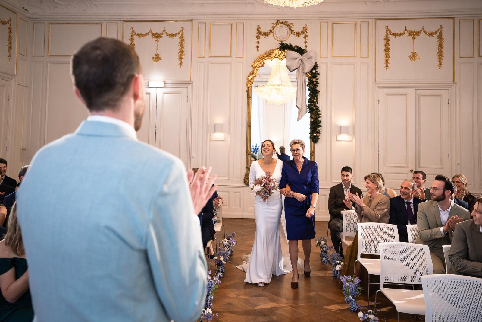Bruid wordt begeleid door moeder tijdens entree ceremonie – emotioneel moment Spaansche Hof Den Haag.