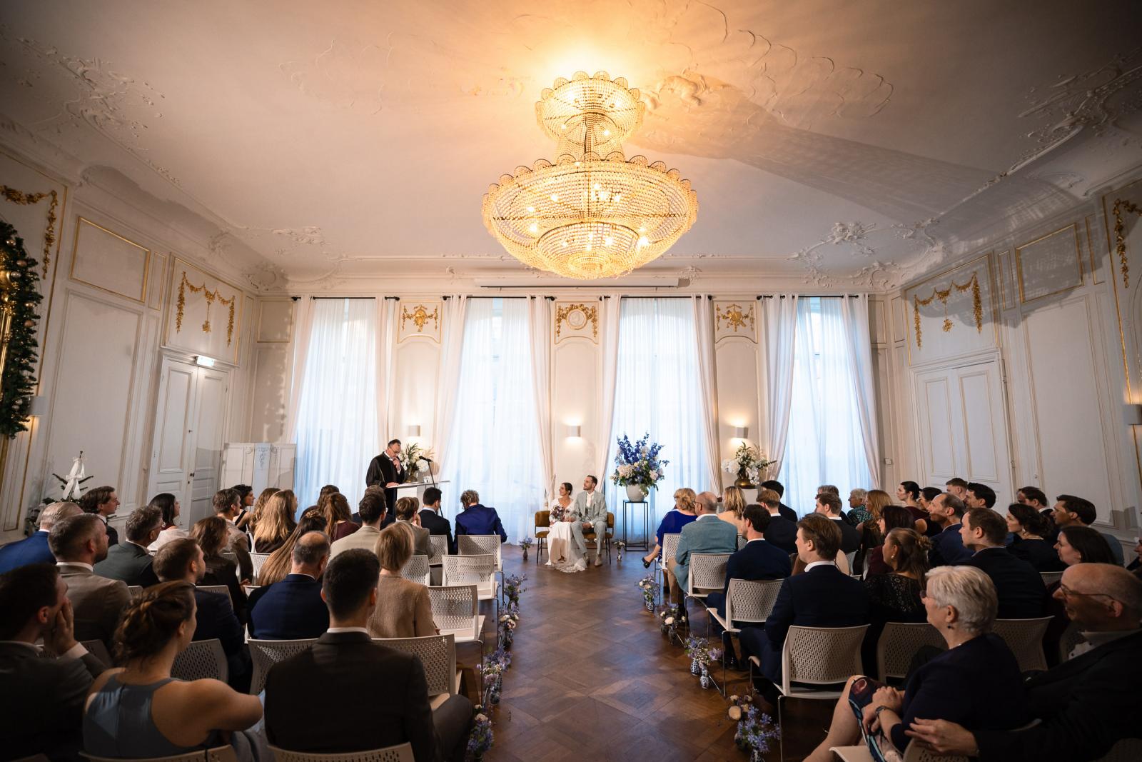 Overzicht van ceremonie met gasten in klassieke zaal – bruiloft Spaansche Hof Den Haag.