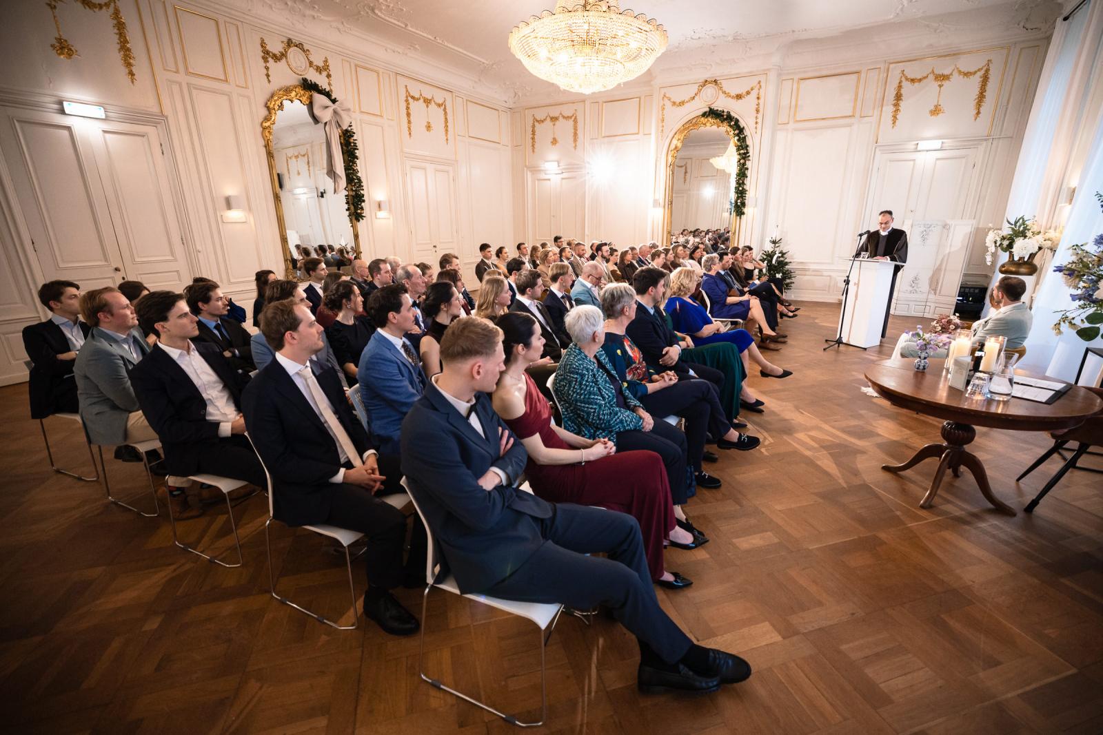Overzicht van gasten tijdens trouwceremonie – sfeervolle bruiloft Spaansche Hof Den Haag.
