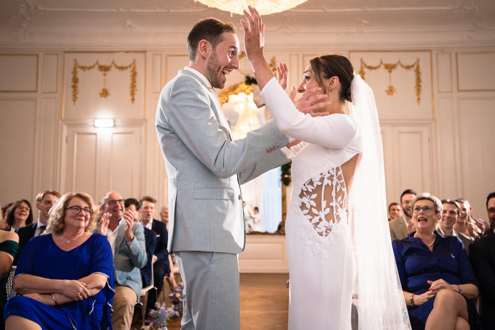 Bruidspaar lacht en reageert op geloften – spontane emoties bruiloft Spaansche Hof Den Haag.