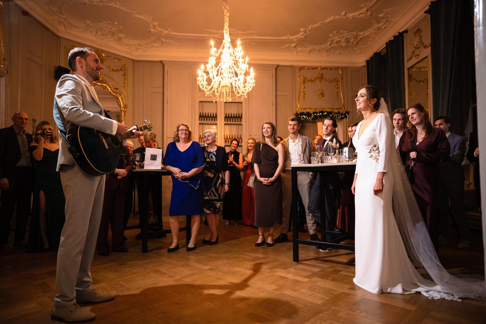 Bruidegom speelt gitaar voor bruid tijdens feestavond – persoonlijke act Spaansche Hof Den Haag.