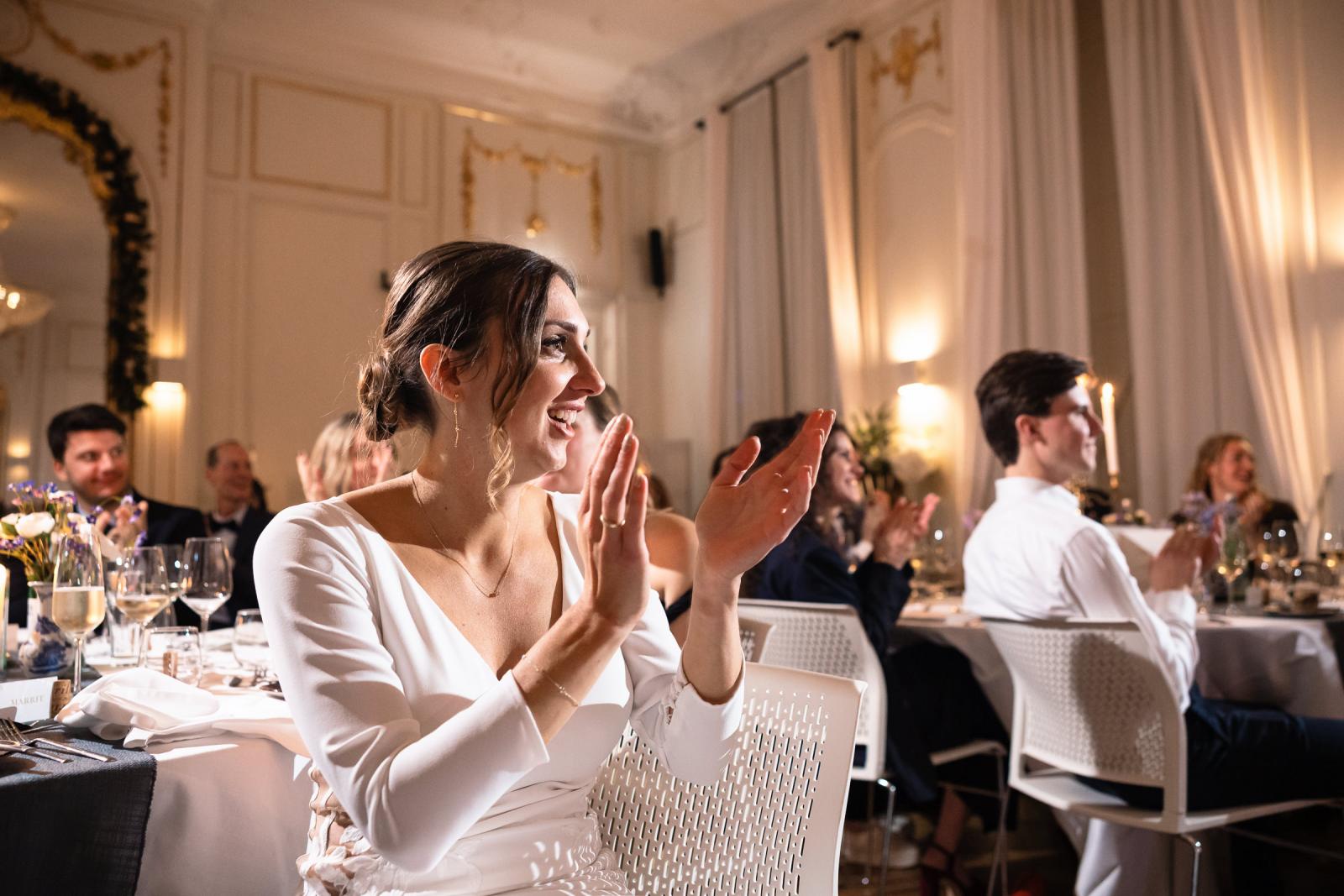 Bruid applaudisseert tijdens het diner – vrolijke sfeer bruiloft Spaansche Hof Den Haag.