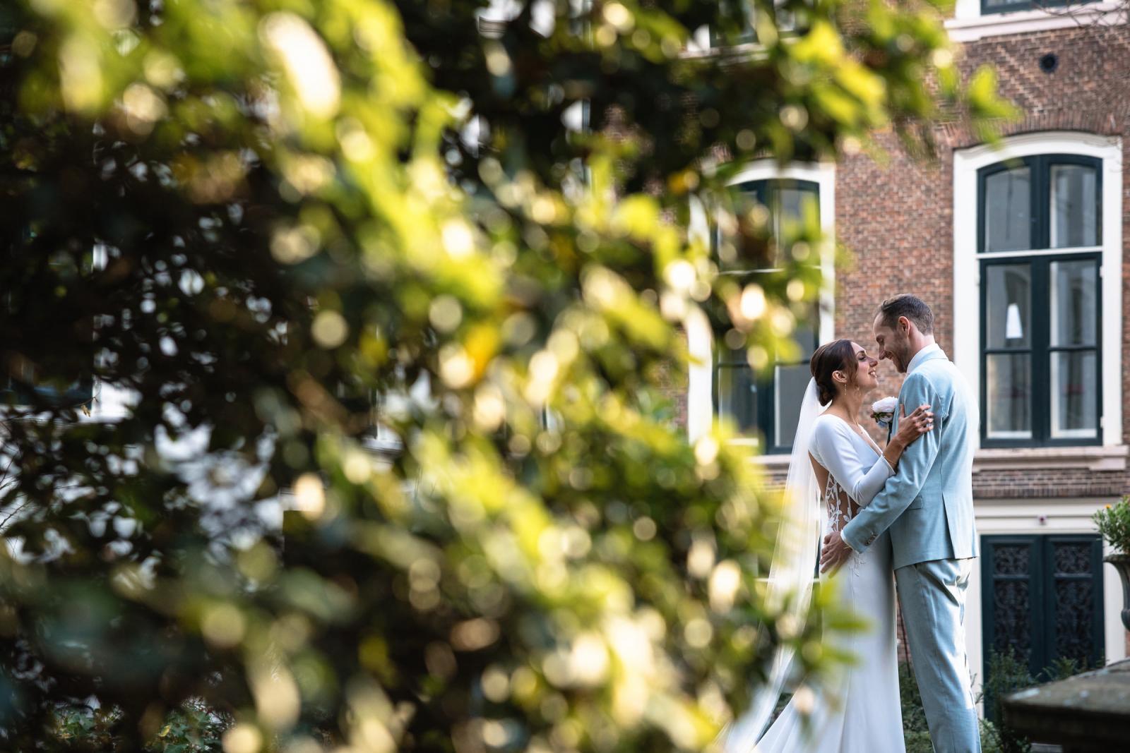 Intiem portret van het bruidspaar omgeven door groen – bruidsfotografie Spaansche Hof Den Haag.